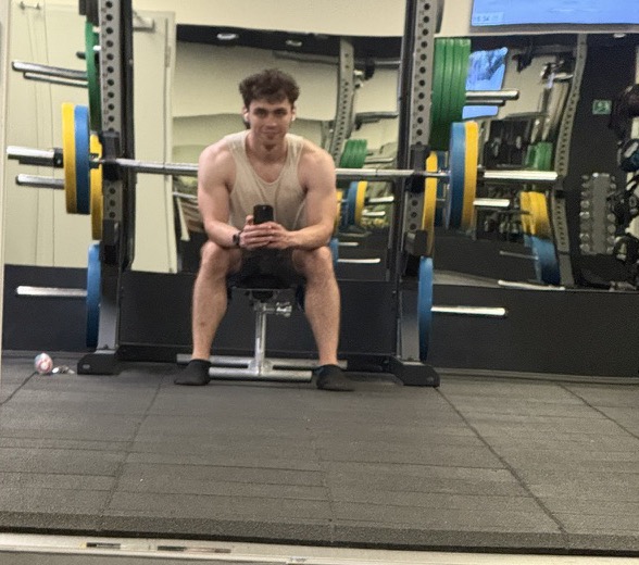 David Novák taking a mirror selfie on a bench in the gym